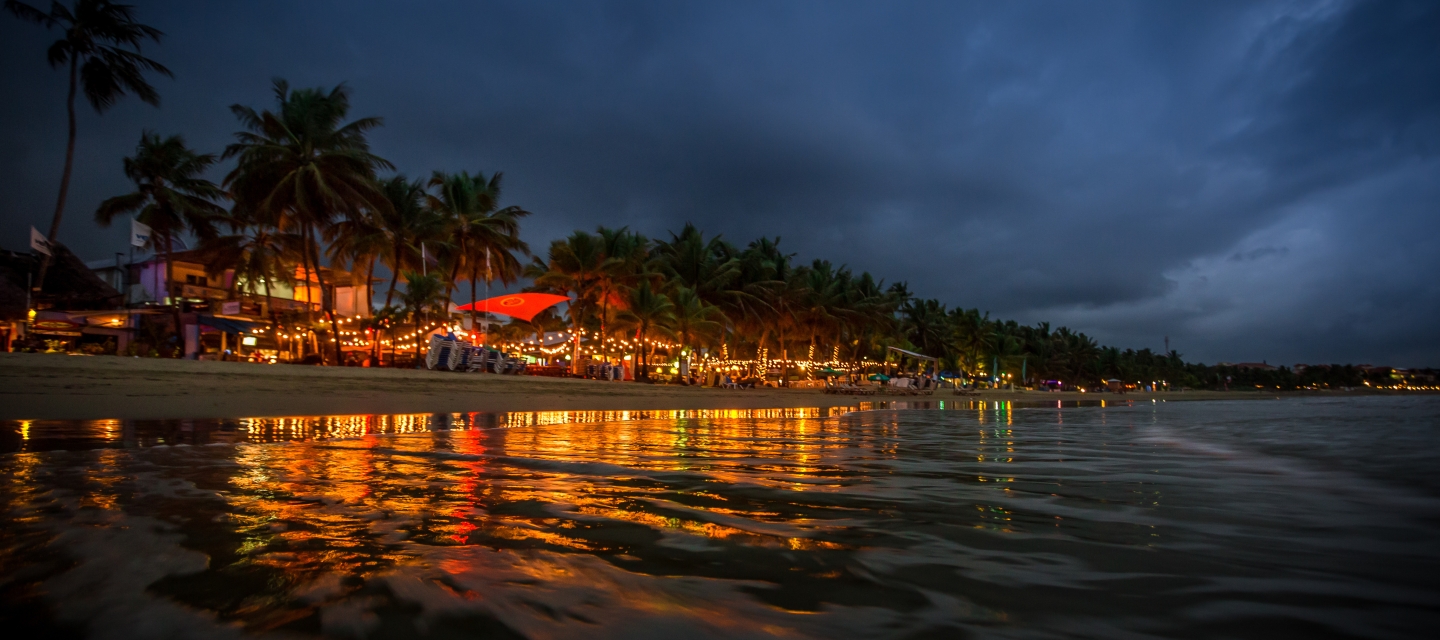 nightime image of beach with lights reflecting on water