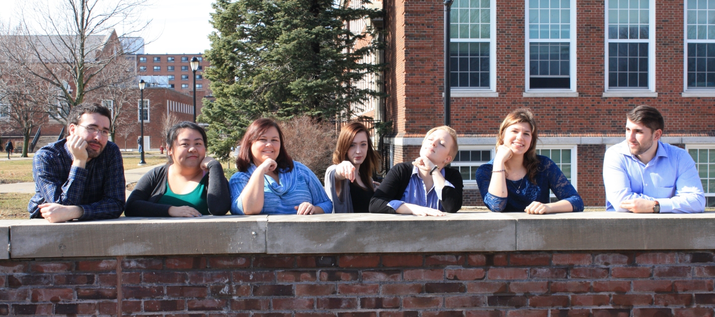 group of students standing behind wall looking at camera